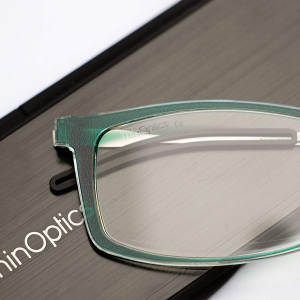ThinOptics reading glasses and a sleek black case: minimalist design with thin lenses. The compact, brushed metal case offers a modern, portable solution for individuals needing reading glasses.