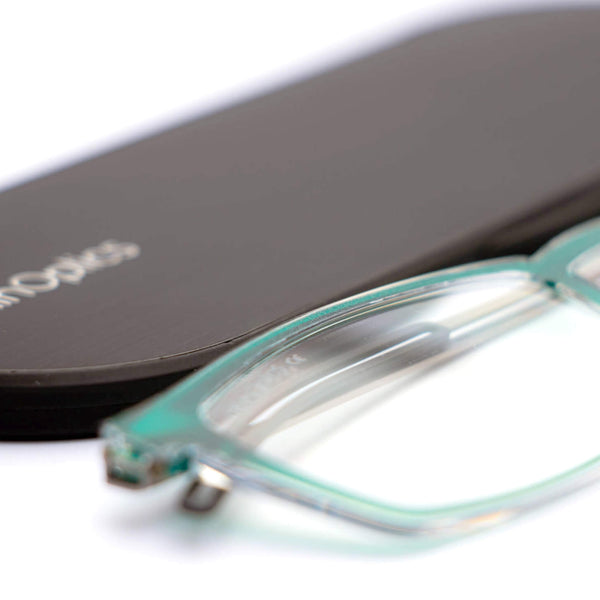 ThinOptics reading glasses and a sleek black case: minimalist design with thin lenses. The compact, brushed metal case offers a modern, portable solution for individuals needing reading glasses.