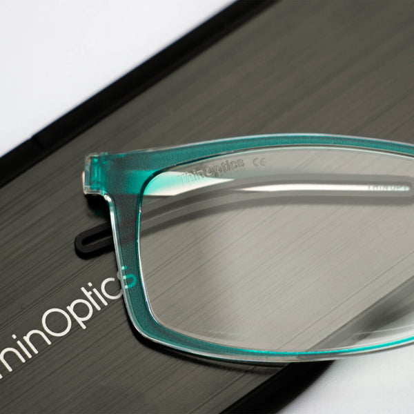 ThinOptics reading glasses and a sleek black case: minimalist design with thin lenses. The compact, brushed metal case offers a modern, portable solution for individuals needing reading glasses.