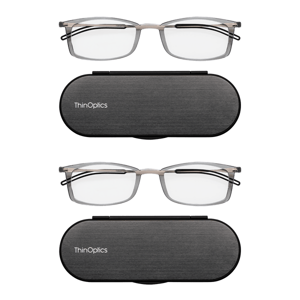 Two pairs of ThinOptics reading glasses rest atop their matching brushed-metal compact cases.