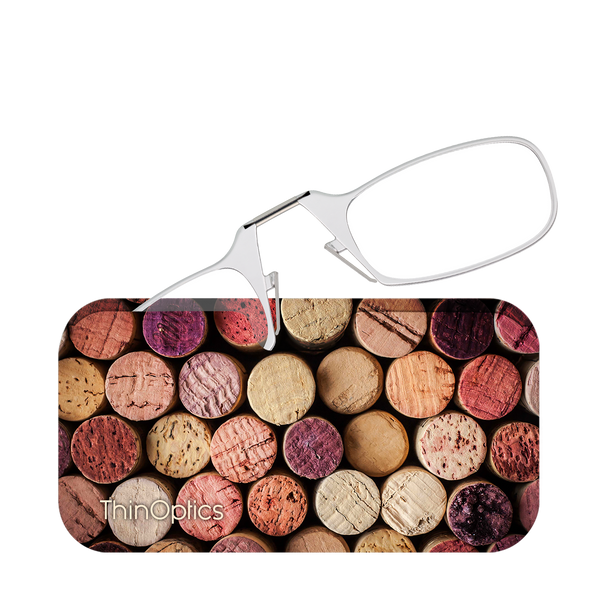 Silver ThinOptics reading glasses rest on a background of assorted wine corks.