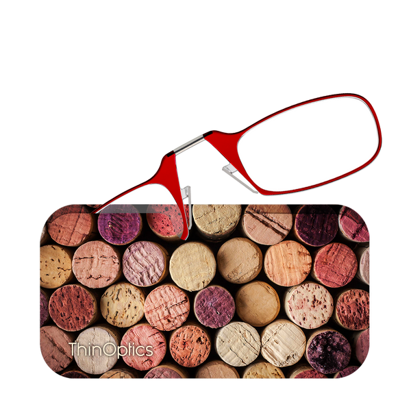 Red ThinOptics reading glasses rest on a background of assorted wine corks.