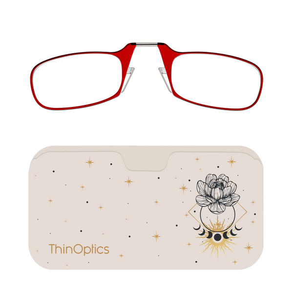 Red reading glasses rest unfolded on a beige case adorned with a celestial design of a blooming flower, moon phases, and stars.