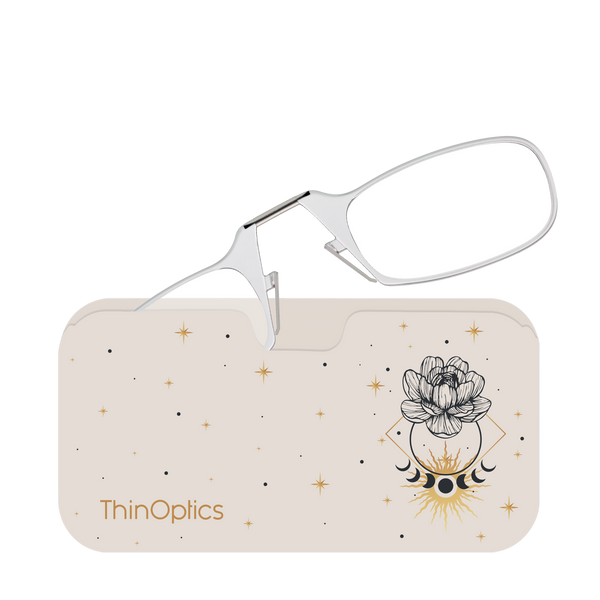Silver ThinOptics reading glasses rest unfolded atop their matching beige case decorated with a celestial design.