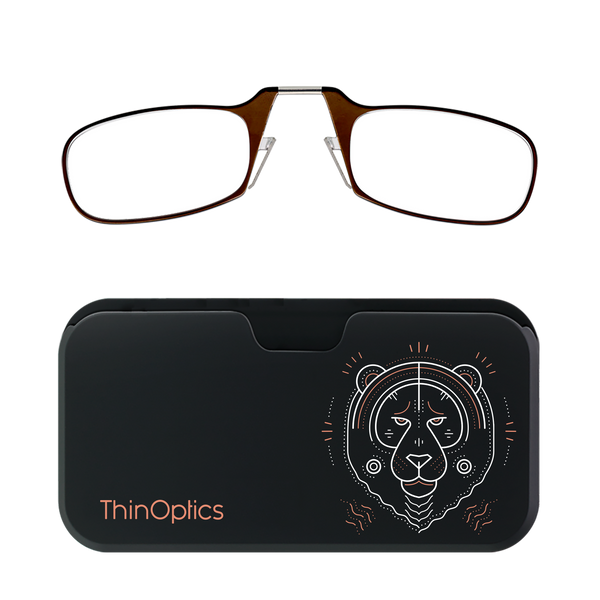 Brown ThinOptics reading glasses folded atop a black carrying case featuring a minimalist copper tiger design.