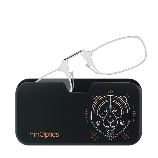 Silver ThinOptics reading glasses rest unfolded on their black carrying case, featuring a stylized tiger design.
