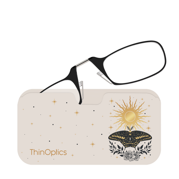 Black ThinOptics reading glasses rest folded on their celestial-themed carrying case.