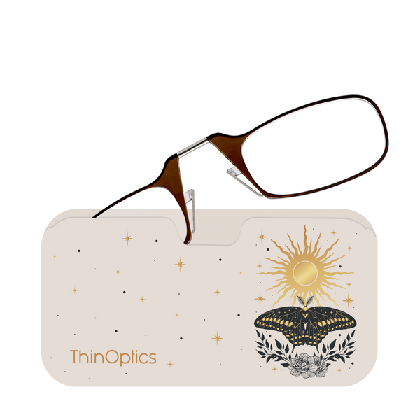 Brown ThinOptics reading glasses rest folded on their matching celestial-themed carrying case.