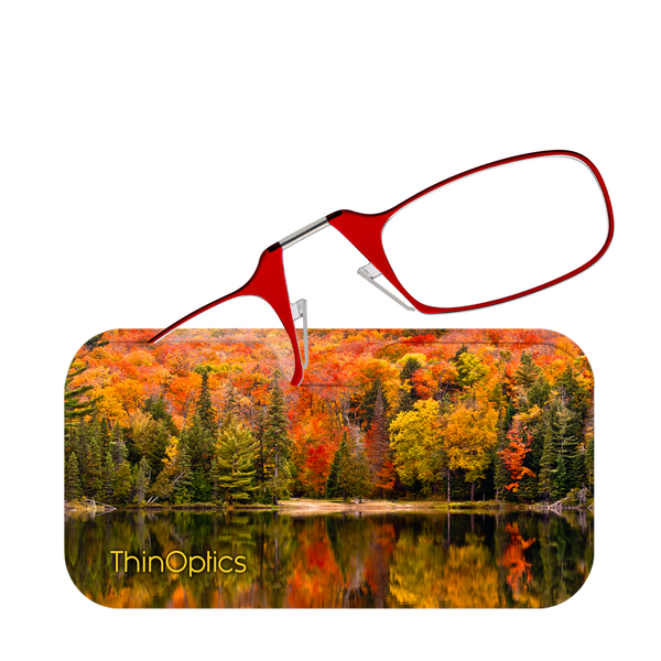 Red ThinOptics reading glasses enhance a view of vibrant autumn foliage reflected in a still lake.
