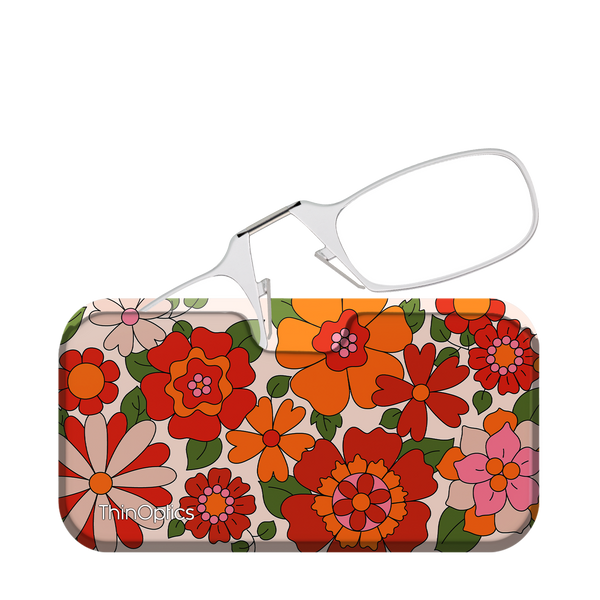 Silver ThinOptics reading glasses rest folded in their compact floral case. The case features a bright, retro floral pattern.
