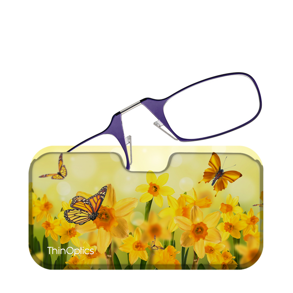 Purple ThinOptics reading glasses folded atop a floral case featuring yellow daffodils and monarch butterflies.