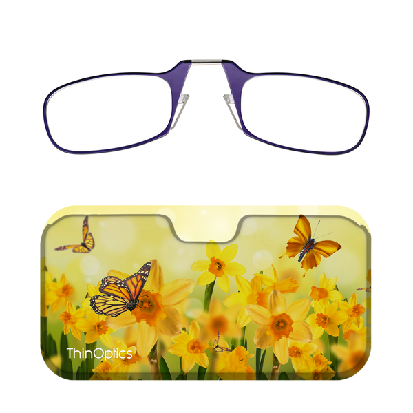 Purple ThinOptics reading glasses folded atop a floral case featuring monarch butterflies fluttering over bright yellow daffodils.