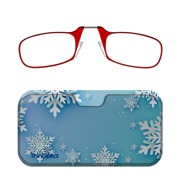 A pair of red reading glasses with a silver bridge folds into a compact blue case decorated with white snowflakes.