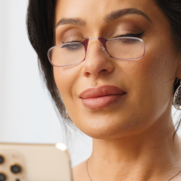 Woman wearing rectangular eyeglasses reads text message on her smartphone.