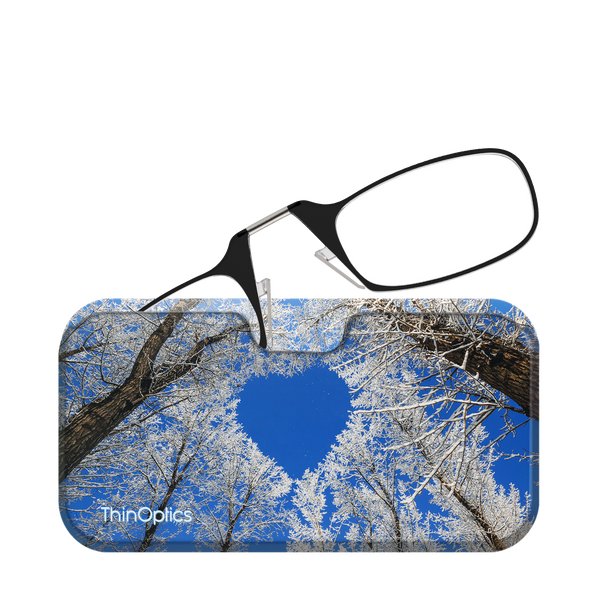 Black ThinOptics reading glasses fold neatly into a slim case featuring a vibrant photo of snow-covered trees against a clear blue sky.