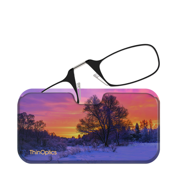 Black ThinOptics reading glasses rest unfolded on their vibrant case featuring a snowy landscape at sunset.