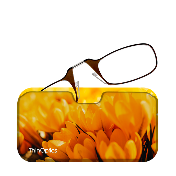 Brown ThinOptics reading glasses rest on a vibrant yellow case featuring a close-up image of blooming yellow crocuses.