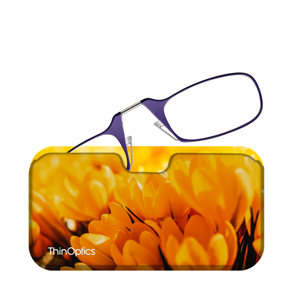 Purple ThinOptics reading glasses rest on a vibrant yellow case featuring a close-up image of blooming crocus flowers.