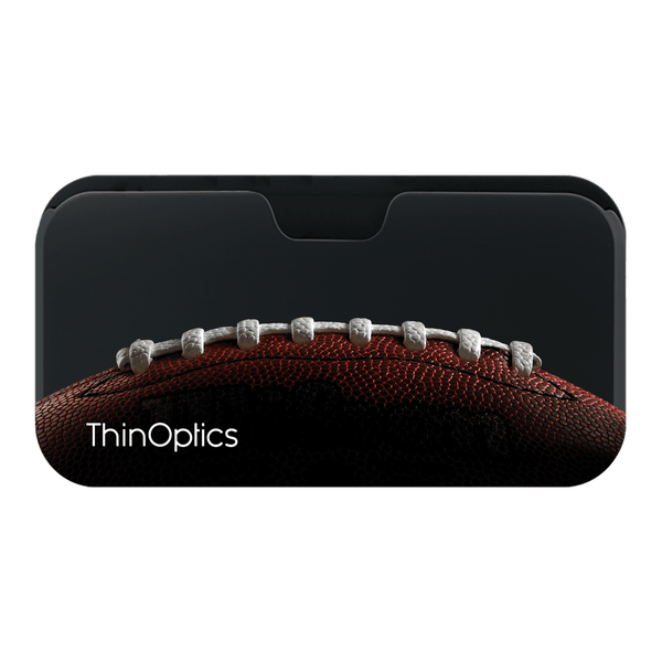 A close-up shot of a football's texture highlights the slim profile of ThinOptics reading glasses tucked into a phone case.