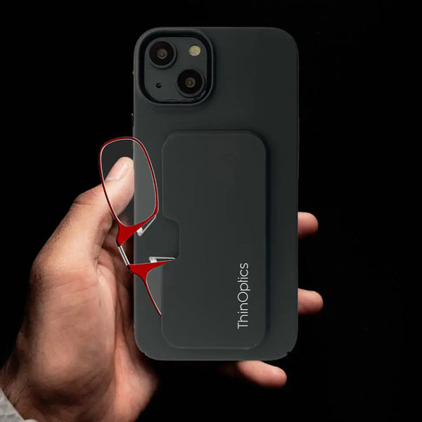 Hand holding a black ThinOptics phone case with a pair of red reading glasses conveniently stored in the back.