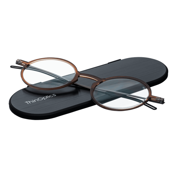 ThinOptics reading glasses and a sleek black case: minimalist design with thin and round lenses. The compact, brushed metal case offers a modern, portable solution for individuals needing reading glasses.