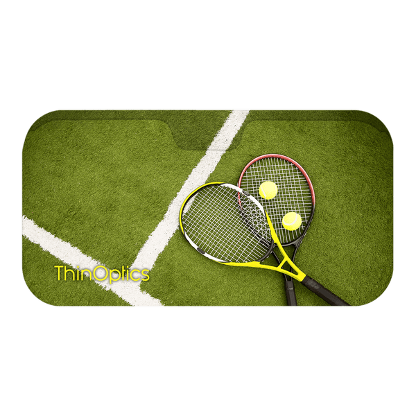 Two tennis rackets and balls rest on a green tennis court.