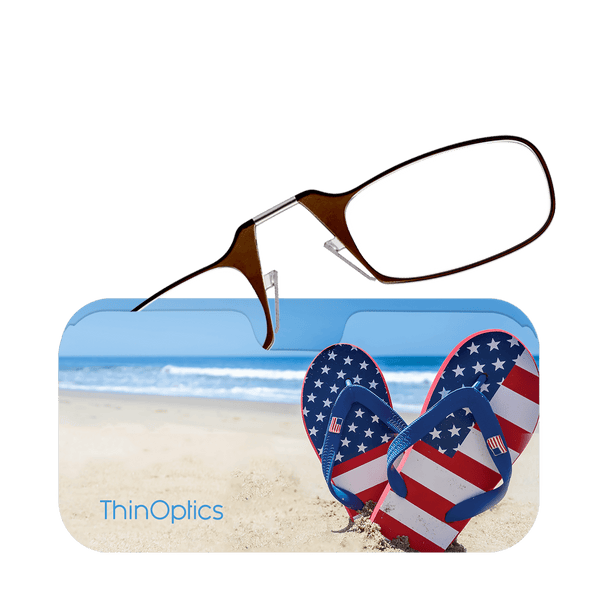 Brown ThinOptics reading glasses rest on a beach-themed case featuring American flag flip flops and a sandy shore.
