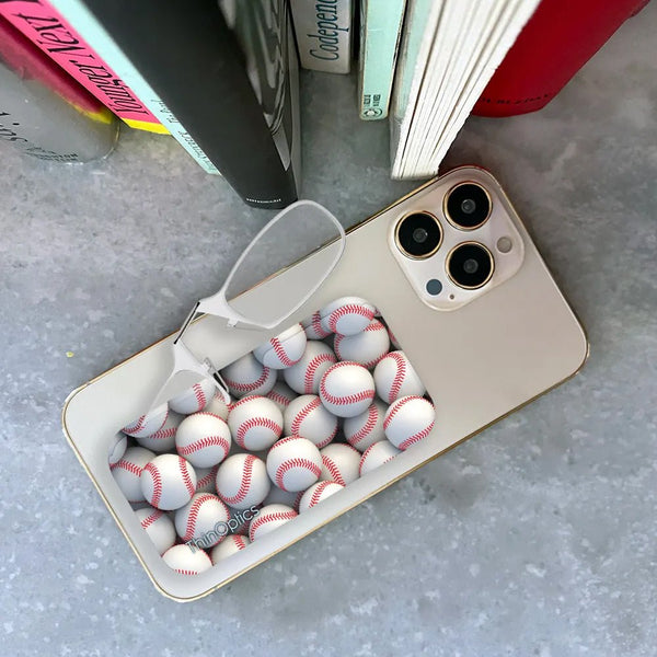 White iPhone with a stack of baseballs tucked under the case and a pair of ThinOptics reading glasses resting on top.