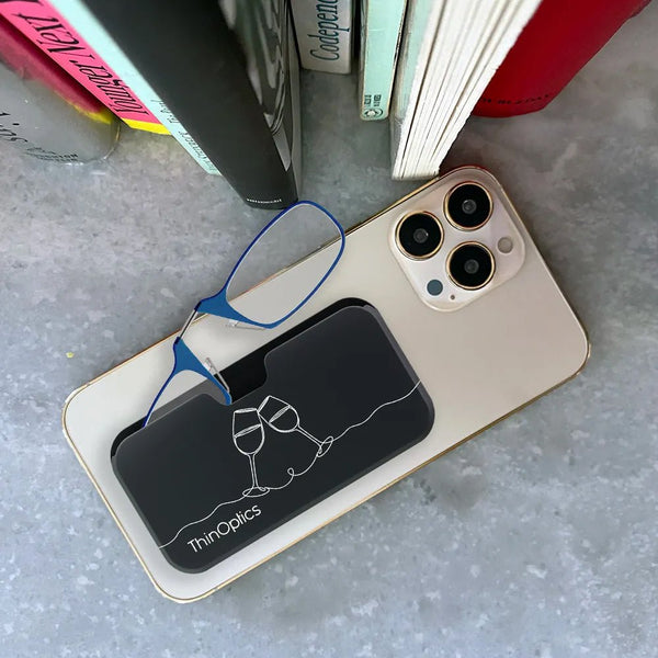 Blue ThinOptics reading glasses rest on their sleek black carrying case atop a smartphone.