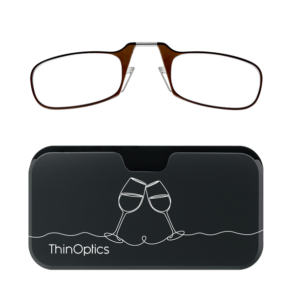 Brown ThinOptics reading glasses rest atop their sleek black case adorned with a minimalist line drawing of toasting wine glasses.