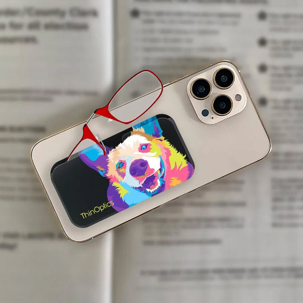 ThinOptics reading glasses with vibrant dog case rest on a smartphone screen.
