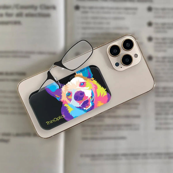 ThinOptics readers rest on a smartphone displaying a colorful illustration of a dog.