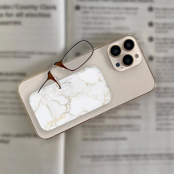 ThinOptics reading glasses with marble-patterned case rest on top of a smartphone.
