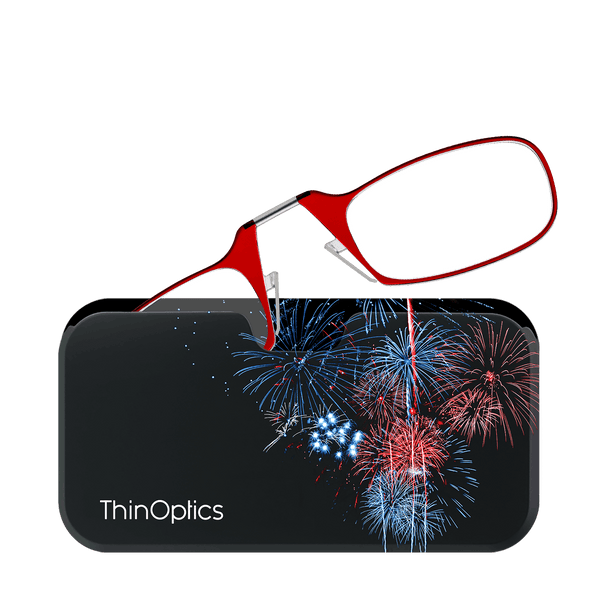 Red ThinOptics reading glasses rest on a black case featuring a vibrant fireworks display.