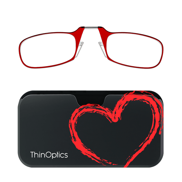 Red ThinOptics reading glasses rest unfolded above their black heart-design carrying case.
