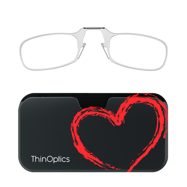 Silver ThinOptics reading glasses rest unfolded above their black case, adorned with a bold, red painted heart.