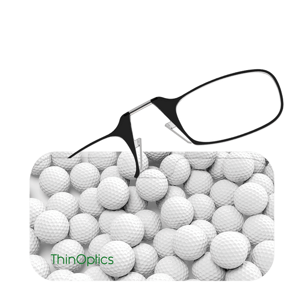 A pair of ThinOptics reading glasses rest on a sea of white golf balls, highlighting their compact and convenient design for golfers.