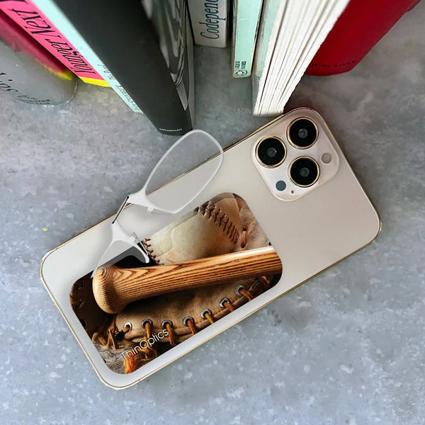 ThinOptics reading glasses rest on a smartphone displaying a vintage baseball and mitt.