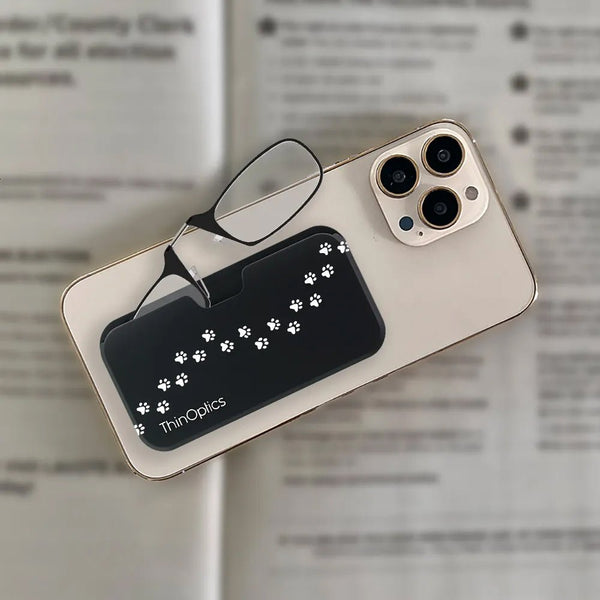 ThinOptics reading glasses with paw print case rest on a smartphone screen.