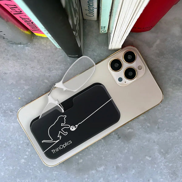 ThinOptics readers rest on a smartphone, showcasing their slim design and convenient carrying case.