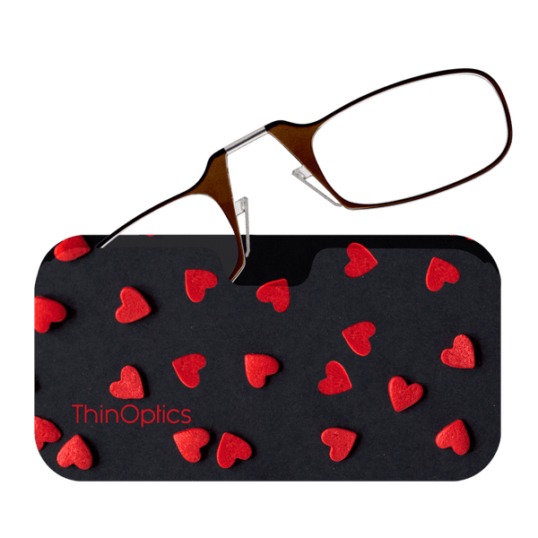 Brown ThinOptics reading glasses rest on a black heart-patterned case.