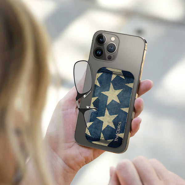 Woman holds smartphone with ThinOptics reading glasses case featuring a vintage American flag design.