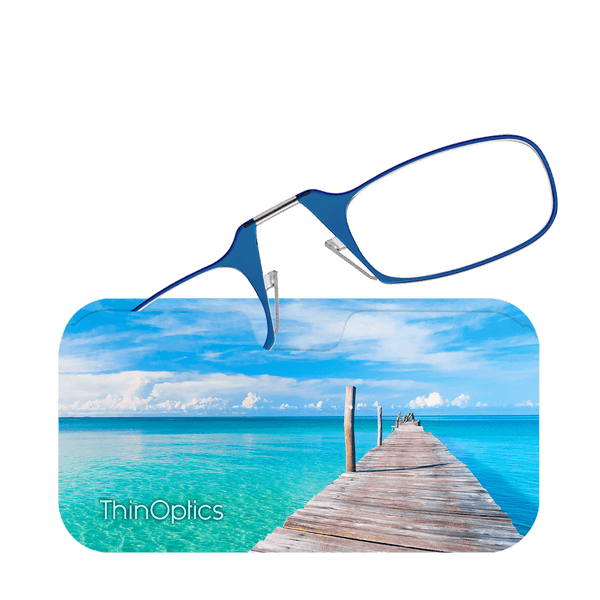Blue ThinOptics reading glasses rest on a slim case featuring a serene image of a wooden pier extending over turquoise ocean water.