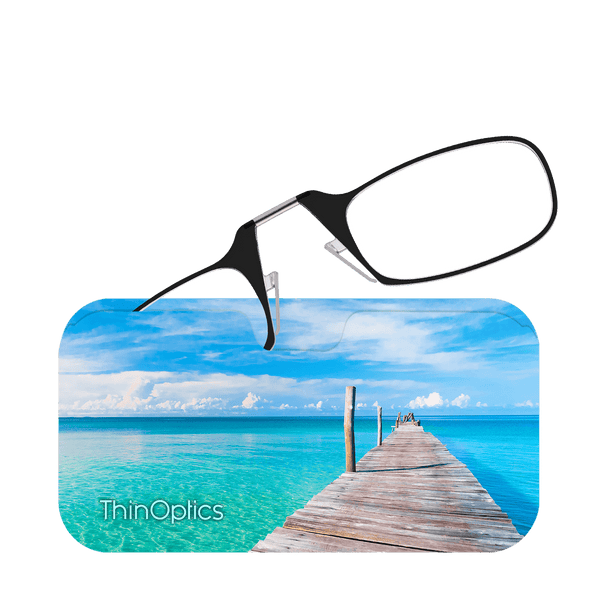 ThinOptics reading glasses rest on a case featuring a wooden pier extending over turquoise ocean water.