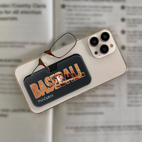 ThinOptics baseball-themed reading glasses rest on a smartphone, demonstrating their compact and portable design.