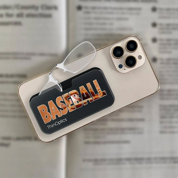 ThinOptics baseball-themed reading glasses rest folded on a phone case, displaying their compact and portable design.
