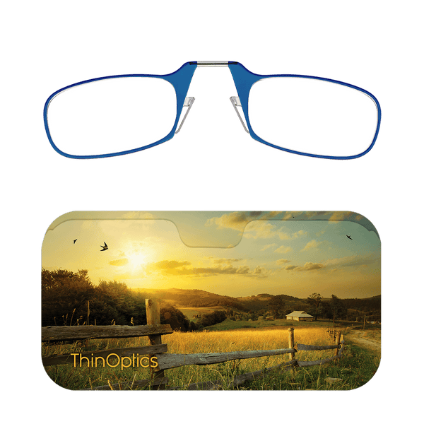 Blue ThinOptics reading glasses folded atop a slim case featuring a sunset over a fence line and grassy field.