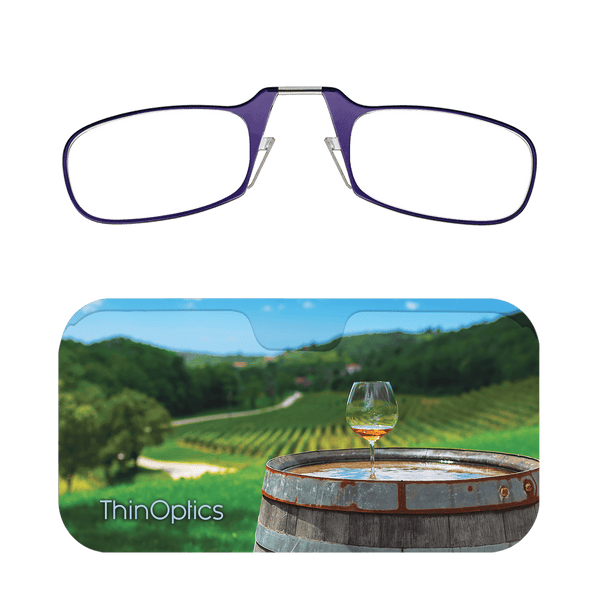 ThinOptics reading glasses rest on a case depicting a vineyard with a glass of wine on a barrel.