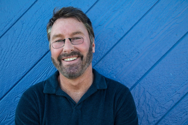 Man wearing ThinOptics Readers against a blue wall background.
