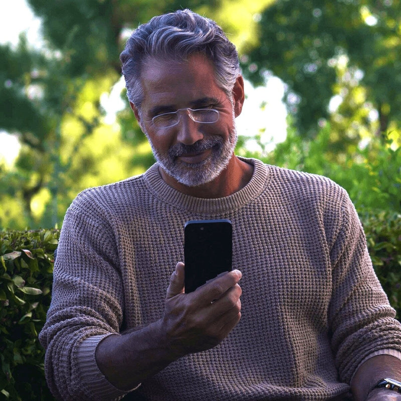 Man wearing ThinOptics Readers and reading on his phone.